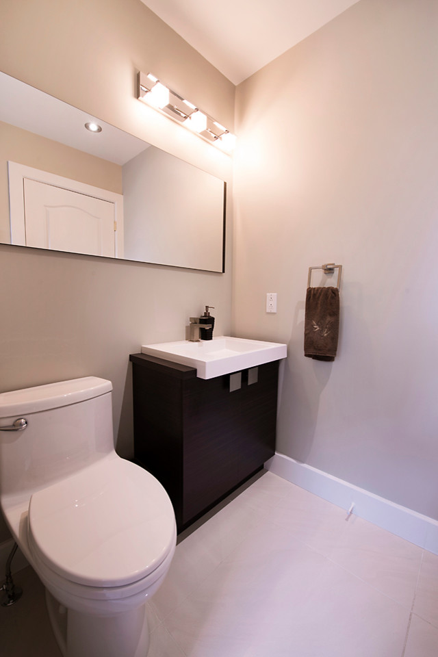 This is an example of a small contemporary single-wall utility room in Other with flat-panel cabinets, dark wood cabinets, grey walls, porcelain floors, a side-by-side washer and dryer and a drop-in sink.