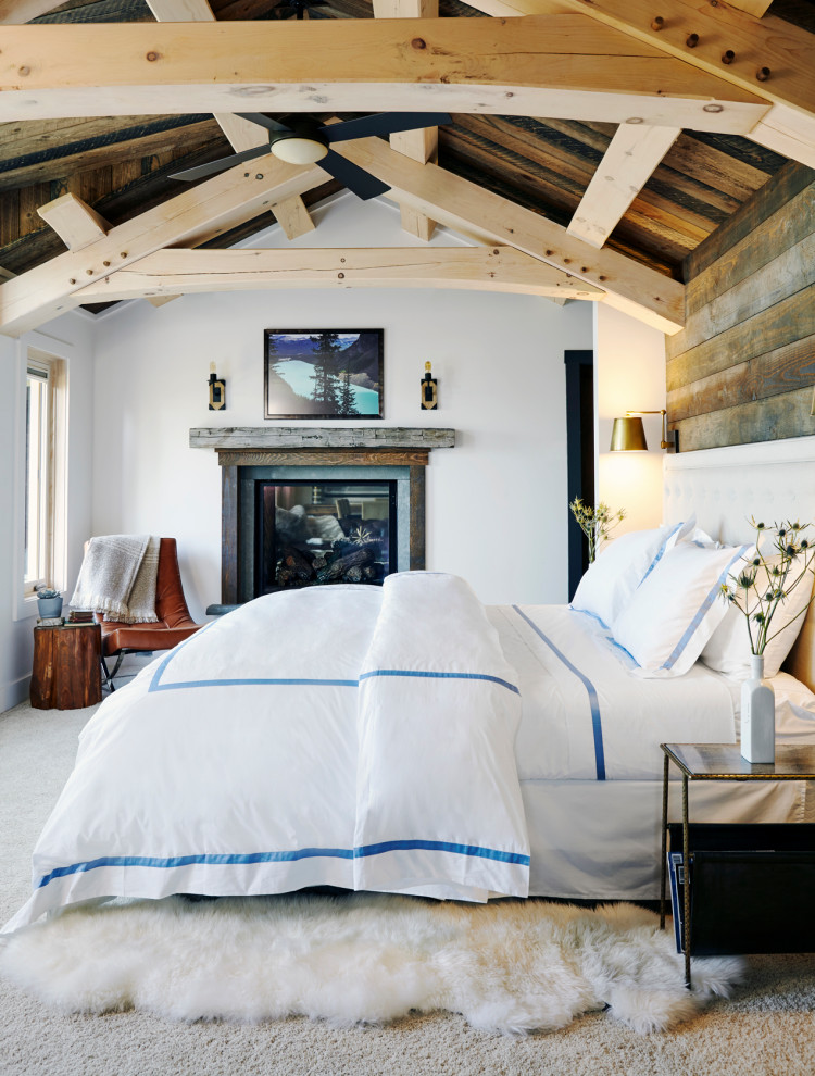 Inspiration for a mid-sized country master bedroom in New York with white walls, carpet, a standard fireplace, a wood fireplace surround, grey floor, vaulted, exposed beam, wood and wood walls.