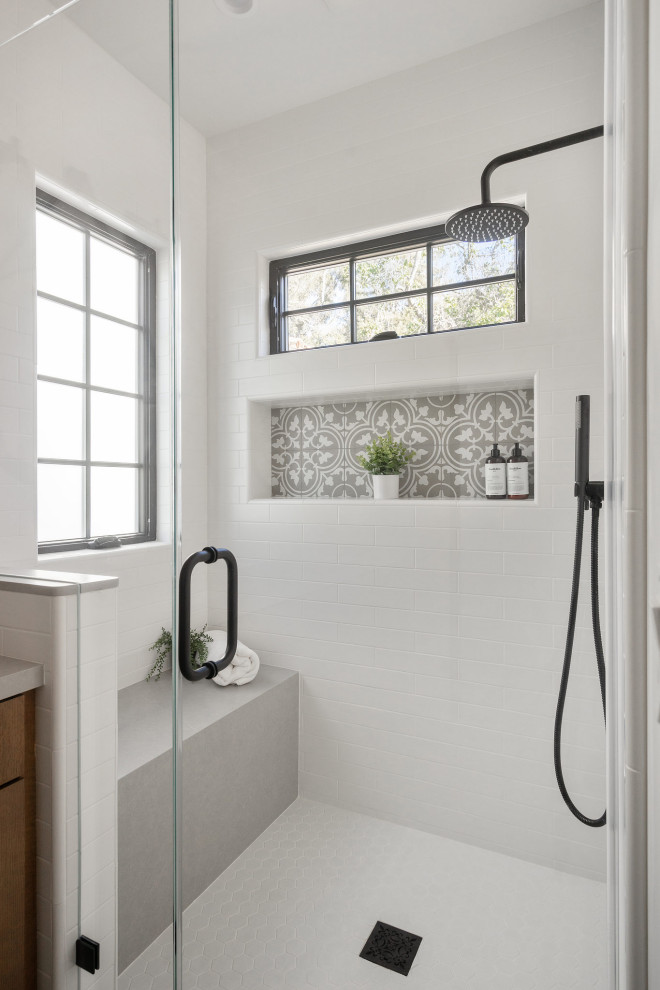 Photo of a mediterranean bathroom in San Francisco with an undermount tub, a shower/bathtub combo, a wall-mount toilet, white walls, ceramic floors, a niche and a freestanding vanity.