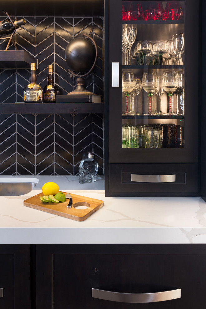 Photo of a small contemporary galley wet bar in Other with an undermount sink, recessed-panel cabinets, black cabinets, quartz benchtops, black splashback, ceramic splashback, porcelain floors, brown floor and white benchtop.