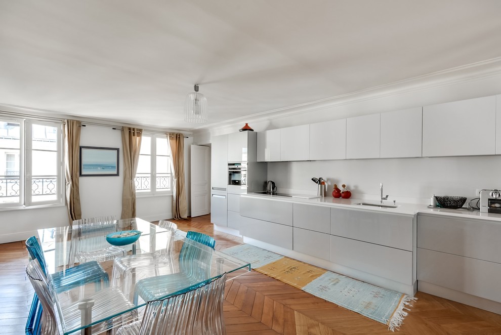This is an example of a large contemporary single-wall eat-in kitchen in Paris with white cabinets and no island.