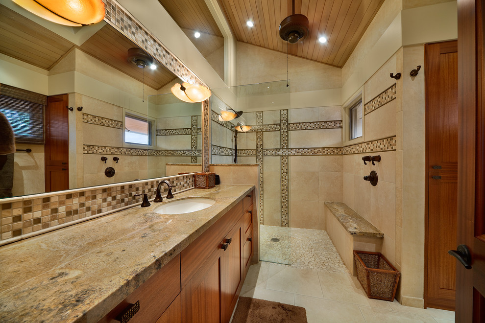 This is an example of a large tropical master bathroom in Hawaii with a curbless shower, mosaic tile, shaker cabinets, medium wood cabinets, brown tile, beige walls, an undermount sink and granite benchtops.