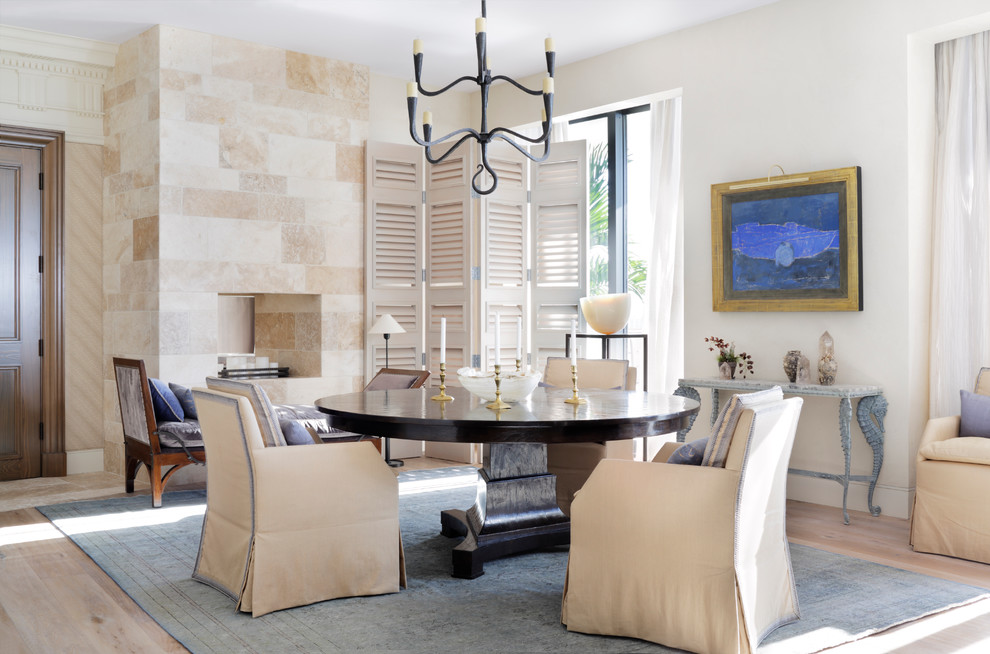 Photo of a transitional dining room in Miami with beige walls, light hardwood floors and a stone fireplace surround.