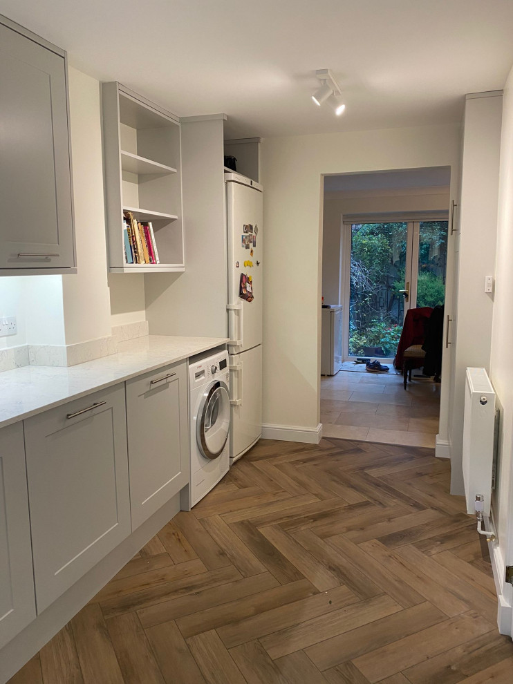 This is an example of a mid-sized contemporary kitchen in London with light hardwood floors and brown floor.