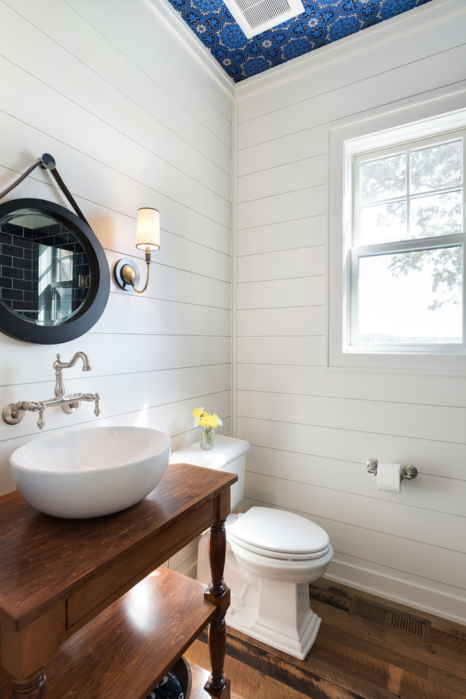 Inspiration for a mid-sized beach style powder room in Minneapolis with a two-piece toilet, white walls, a vessel sink, wood benchtops, brown floor, furniture-like cabinets, dark wood cabinets, dark hardwood floors and brown benchtops.