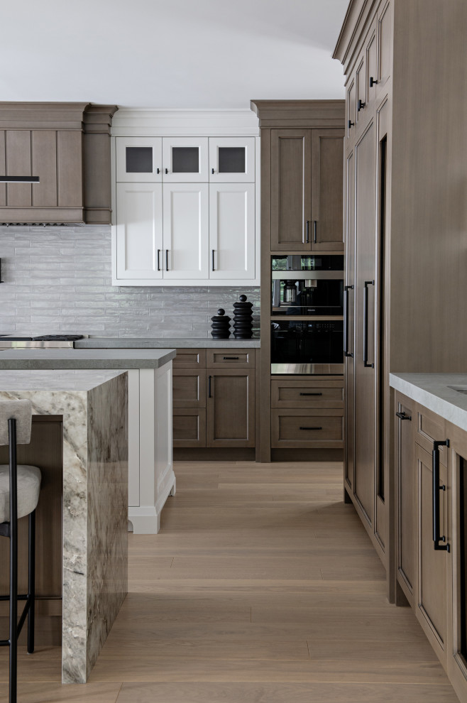 Mid-sized transitional l-shaped medium tone wood floor eat-in kitchen photo in Toronto with recessed-panel cabinets, medium tone wood cabinets, black appliances, two islands and multicolored countertops