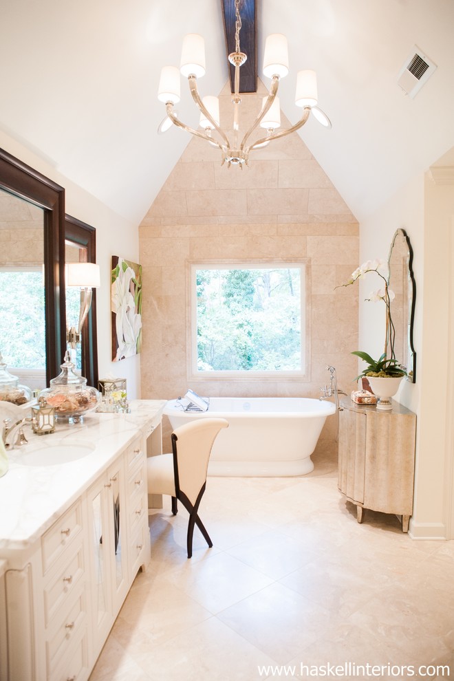 This is an example of a mid-sized transitional master bathroom in Other with an undermount sink, recessed-panel cabinets, white cabinets, marble benchtops, a freestanding tub, a corner shower, a one-piece toilet, beige tile, stone tile, beige walls and limestone floors.