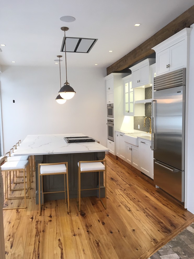 Photo of an expansive transitional single-wall eat-in kitchen in Bridgeport with a farmhouse sink, shaker cabinets, white cabinets, quartz benchtops, brown splashback, ceramic splashback, stainless steel appliances, light hardwood floors, with island, yellow floor and white benchtop.