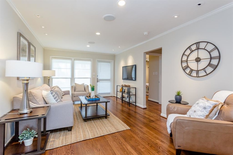 This is an example of a small transitional enclosed living room in Houston with beige walls, medium hardwood floors, no fireplace, a wall-mounted tv and brown floor.