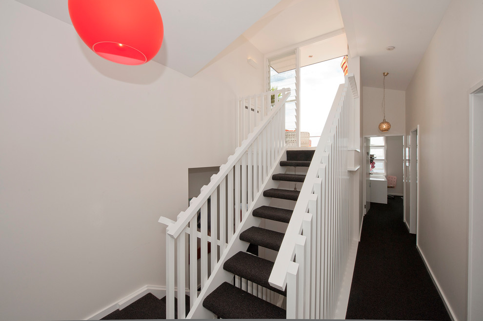Photo of a mid-sized contemporary carpeted u-shaped staircase in Sydney with open risers.