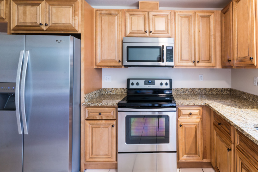 Mid-sized l-shaped eat-in kitchen photo with an undermount sink, raised-panel cabinets, medium tone wood cabinets, granite countertops, ceramic backsplash, stainless steel appliances, a peninsula and brown countertops