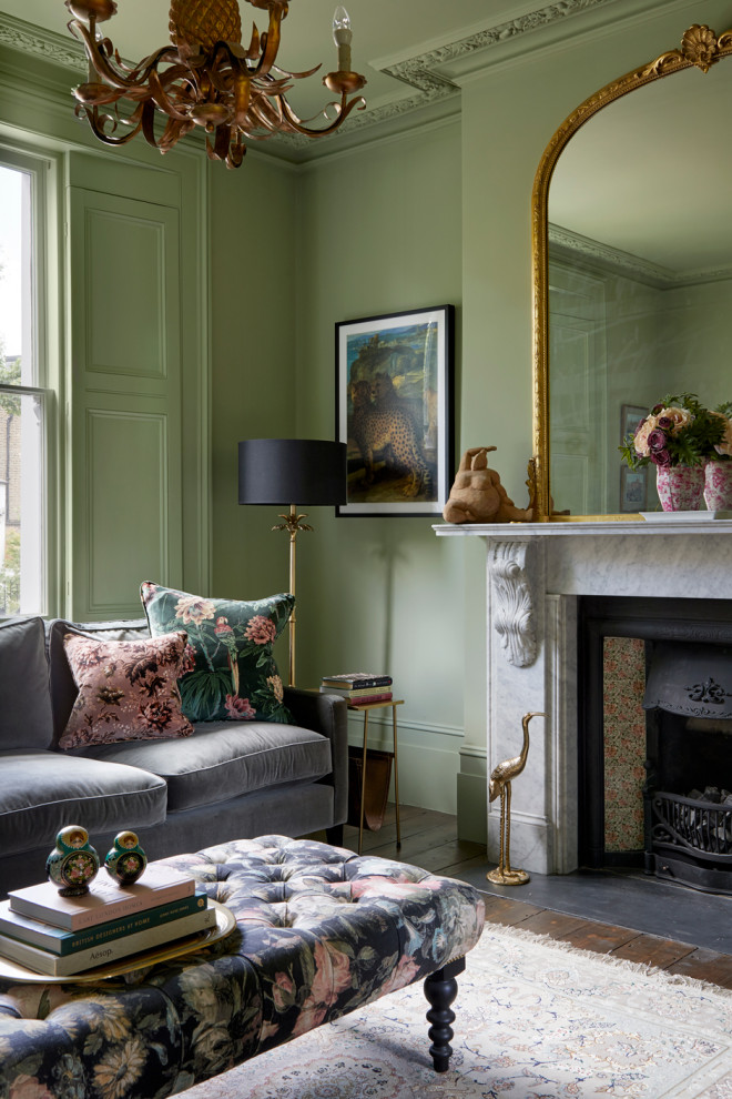 Inspiration for a mid-sized traditional formal living room in London with green walls, dark hardwood floors, a standard fireplace, a stone fireplace surround and brown floor.