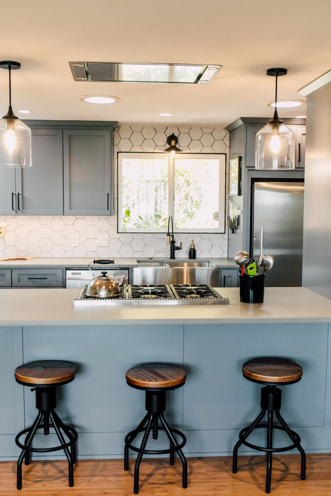 Design ideas for a small eclectic galley open plan kitchen in Seattle with a farmhouse sink, shaker cabinets, blue cabinets, quartz benchtops, white splashback, ceramic splashback, stainless steel appliances, bamboo floors, brown floor and grey benchtop.