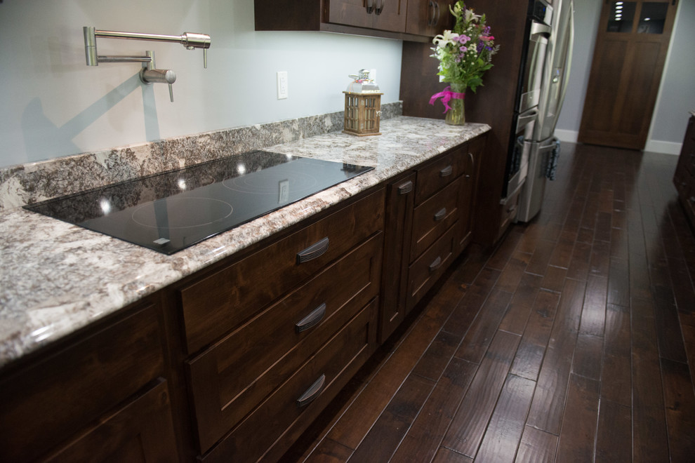 Transitional l-shaped open concept kitchen photo with an undermount sink, shaker cabinets, dark wood cabinets, granite countertops, stainless steel appliances, an island and multicolored countertops