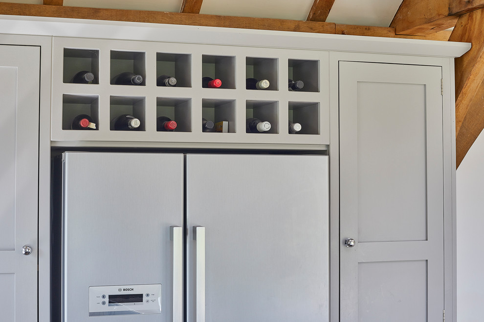 Photo of a large traditional u-shaped kitchen/diner in Surrey with a double-bowl sink, shaker cabinets, grey cabinets, composite countertops, white splashback, porcelain splashback, stainless steel appliances, travertine flooring, an island, beige floors and white worktops.