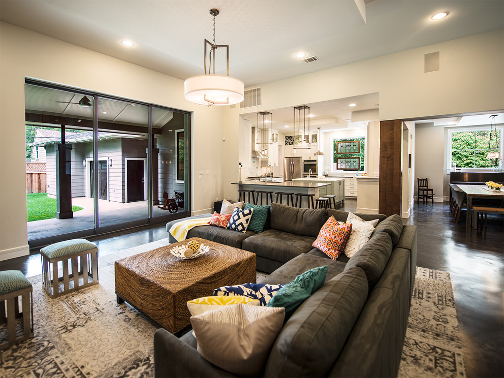 This is an example of a transitional open concept living room in Austin with beige walls and concrete floors.