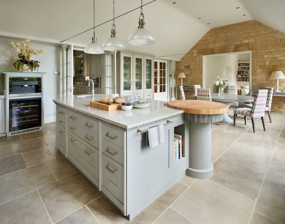 This is an example of a large transitional u-shaped eat-in kitchen in Other with an integrated sink, flat-panel cabinets, beige cabinets, solid surface benchtops, beige splashback, glass sheet splashback, stainless steel appliances, travertine floors, with island and grey floor.