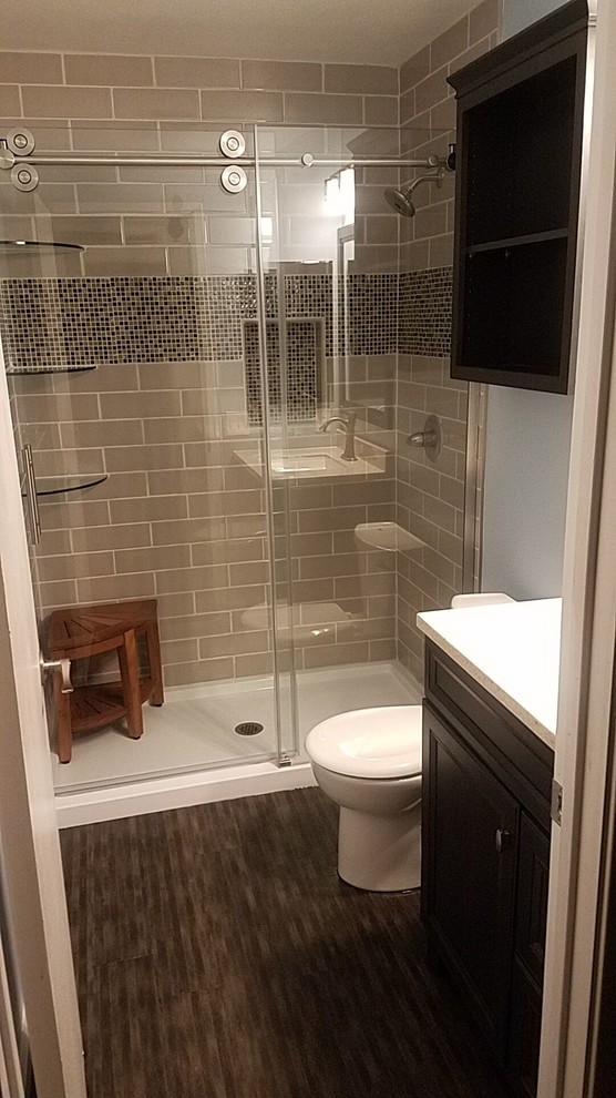 This is an example of a small transitional 3/4 bathroom in Sacramento with raised-panel cabinets, dark wood cabinets, an alcove shower, a one-piece toilet, beige tile, ceramic tile, grey walls, dark hardwood floors, brown floor, a sliding shower screen, grey benchtops and an undermount sink.
