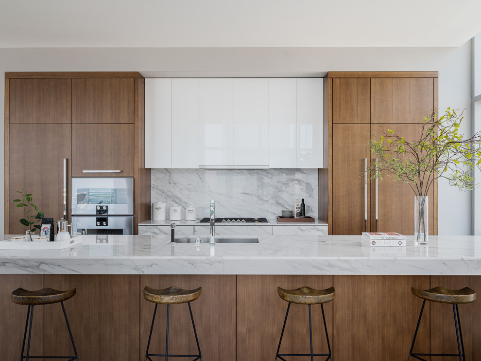 Photo of a contemporary kitchen in New York with an undermount sink, flat-panel cabinets, light wood cabinets, marble benchtops, white splashback, marble splashback, with island and white benchtop.