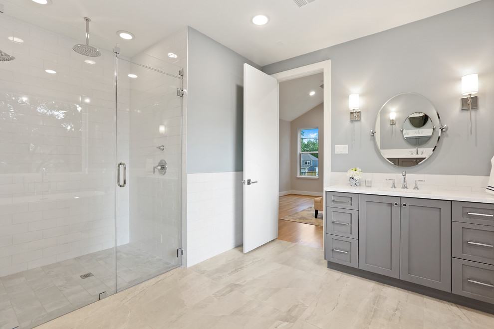 This is an example of a country master bathroom in Houston with shaker cabinets, grey cabinets, a freestanding tub, a corner shower, a one-piece toilet, white tile, subway tile, grey walls, porcelain floors, an undermount sink, engineered quartz benchtops, grey floor, a hinged shower door and white benchtops.