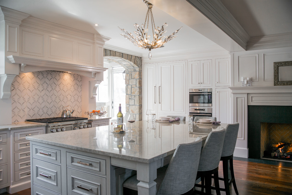 This is an example of a traditional kitchen in Philadelphia with beaded inset cabinets, white cabinets, multi-coloured splashback, stainless steel appliances, dark hardwood floors, with island, brown floor and quartzite benchtops.