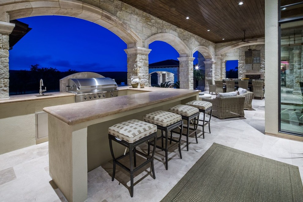 This is an example of an expansive mediterranean backyard patio in Austin with an outdoor kitchen and a roof extension.