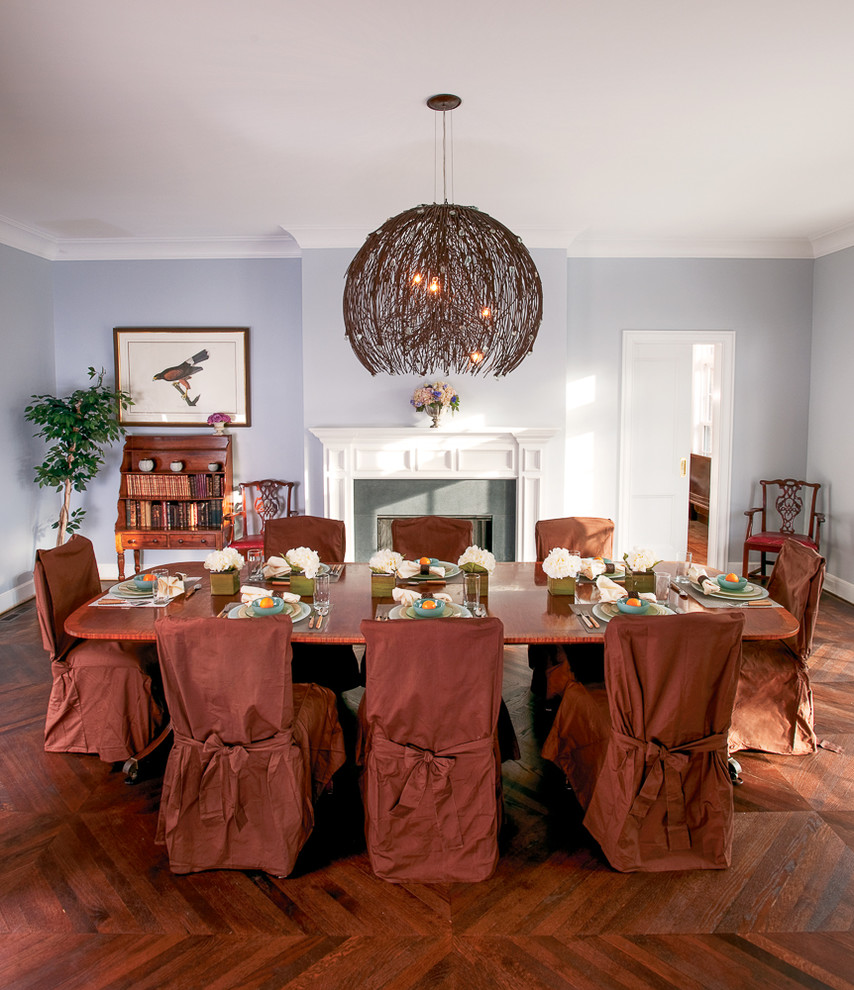 Photo of a large traditional separate dining room in New York with blue walls, dark hardwood floors and a standard fireplace.