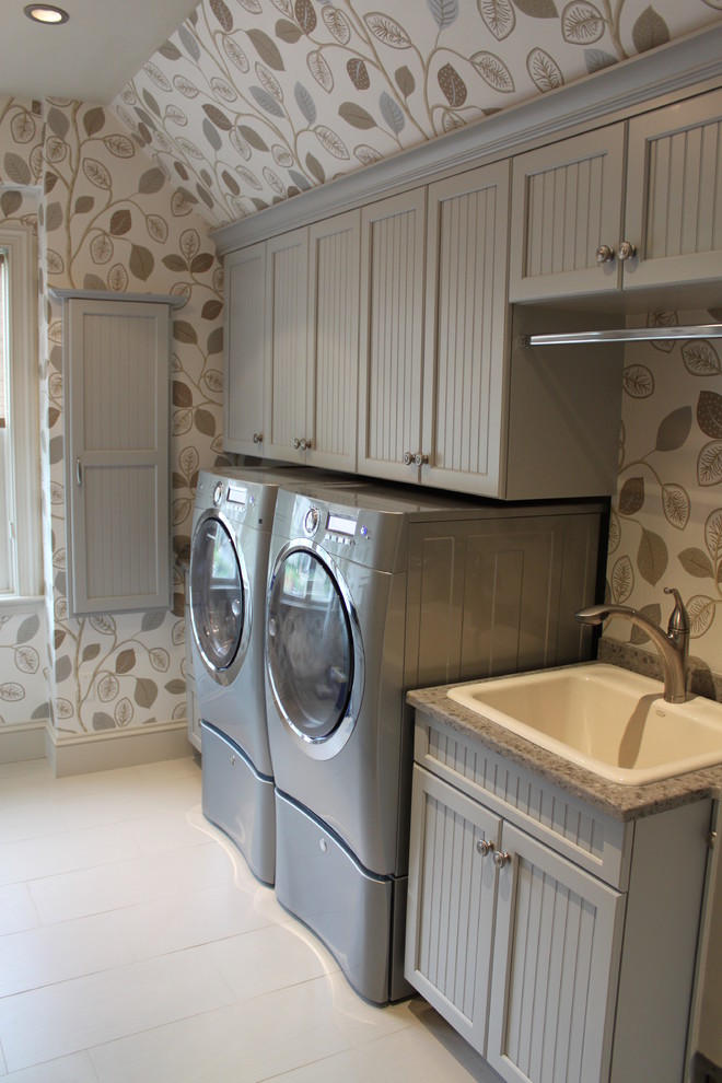 Traditional galley dedicated laundry room in Boston with a drop-in sink, recessed-panel cabinets, grey cabinets, beige walls, porcelain floors and a side-by-side washer and dryer.