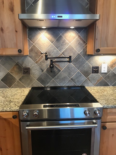Mid-sized mountain style u-shaped concrete floor and brown floor open concept kitchen photo in Austin with a farmhouse sink, recessed-panel cabinets, medium tone wood cabinets, granite countertops, gray backsplash, ceramic backsplash, stainless steel appliances and a peninsula