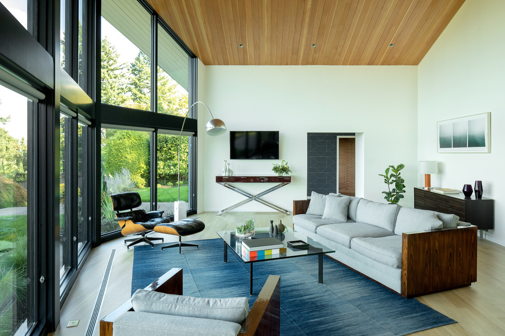 Design ideas for a mid-sized midcentury open concept living room in Portland with white walls, light hardwood floors, a wall-mounted tv, brown floor and a two-sided fireplace.