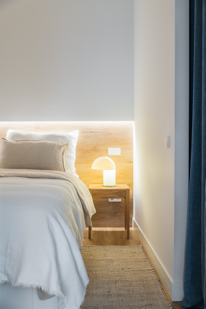 Ejemplo de dormitorio principal y beige y blanco actual de tamaño medio sin chimenea con paredes blancas, suelo de madera en tonos medios, suelo beige y ladrillo
