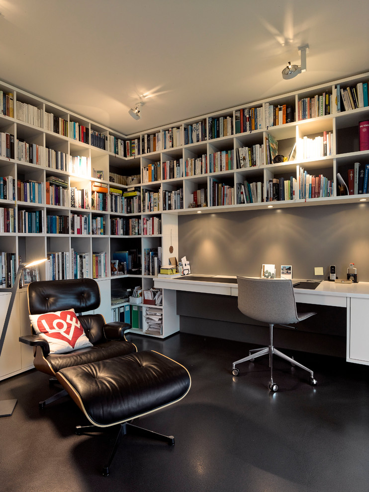 Mid-sized contemporary home office in Stuttgart with a library, grey walls, linoleum floors, no fireplace, a built-in desk and black floor.