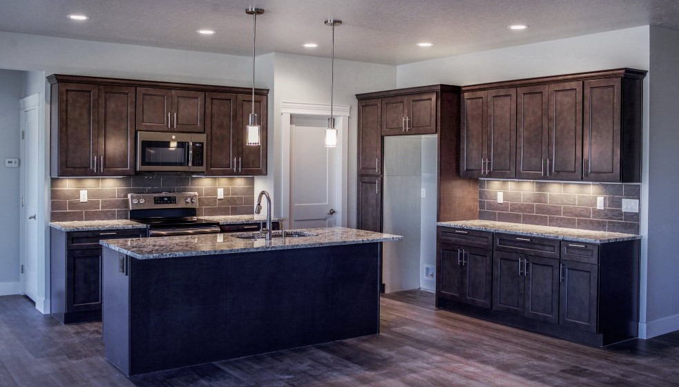 Eat-in kitchen - mid-sized l-shaped eat-in kitchen idea with a double-bowl sink, shaker cabinets, brown cabinets, granite countertops, stone tile backsplash, stainless steel appliances, an island and multicolored countertops