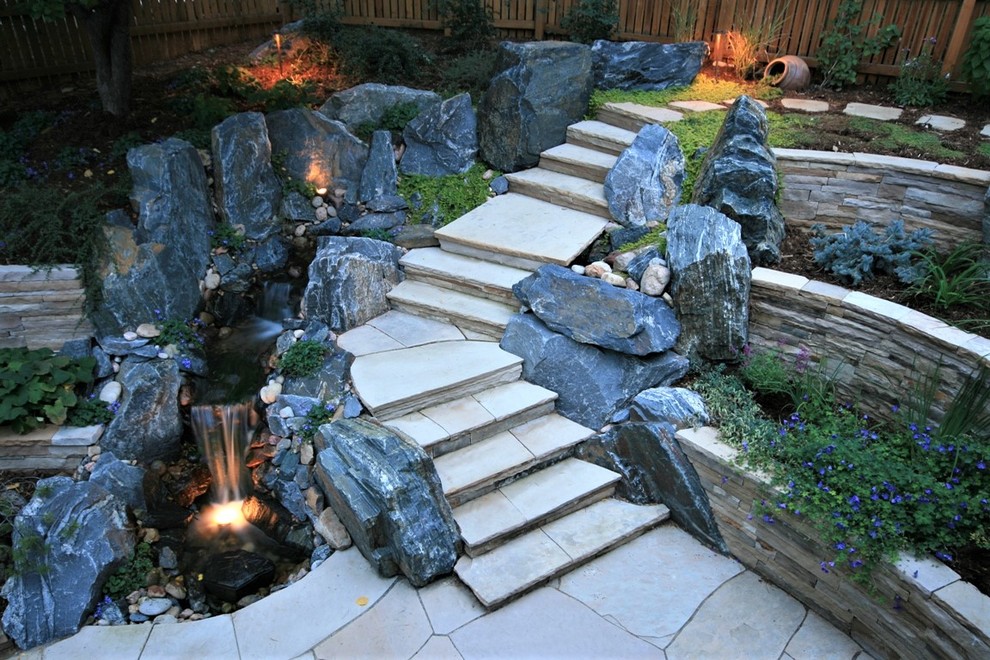 Photo of a mid-sized transitional backyard partial sun formal garden for summer in Denver with a retaining wall and natural stone pavers.