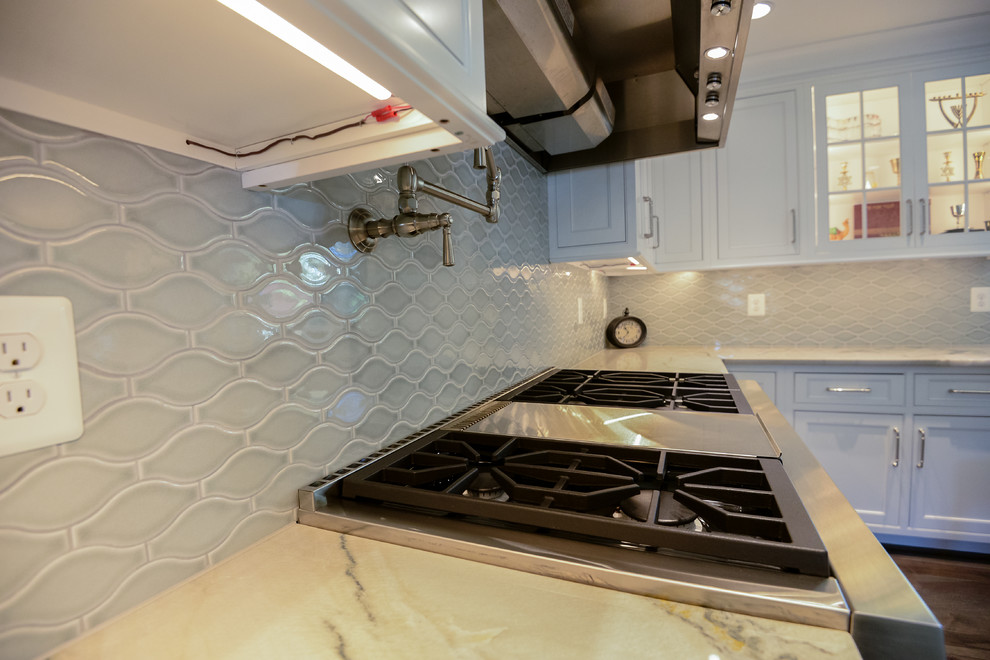 Eat-in kitchen - large transitional u-shaped medium tone wood floor and brown floor eat-in kitchen idea in DC Metro with a farmhouse sink, recessed-panel cabinets, white cabinets, marble countertops, stainless steel appliances, an island, gray backsplash and porcelain backsplash