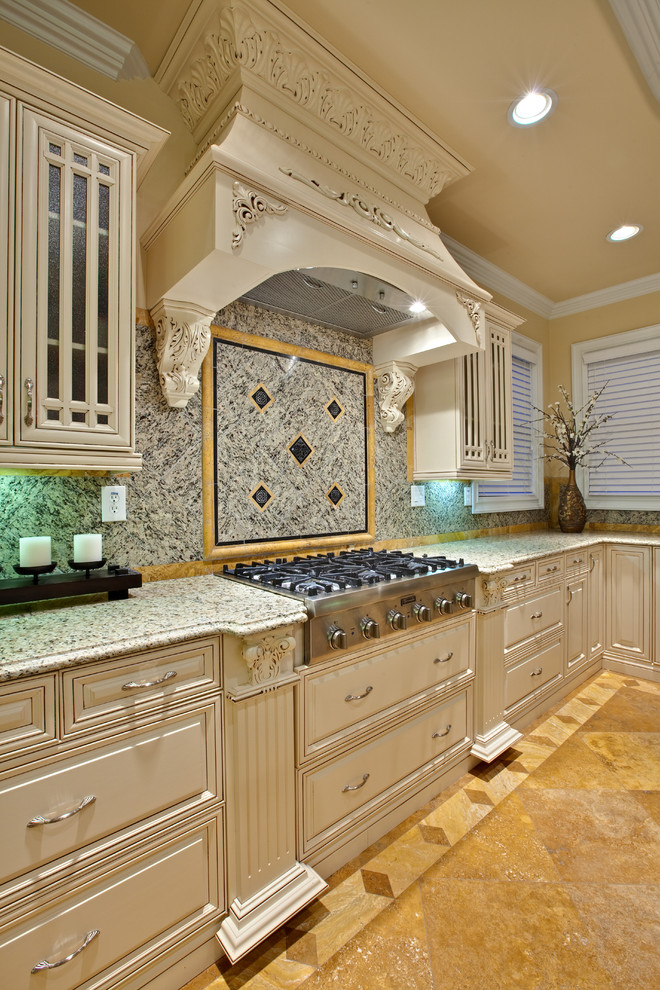 Design ideas for an expansive traditional l-shaped eat-in kitchen in Atlanta with glass-front cabinets, white cabinets, an undermount sink, granite benchtops, multi-coloured splashback, granite splashback, stainless steel appliances, travertine floors, with island, brown floor and beige benchtop.