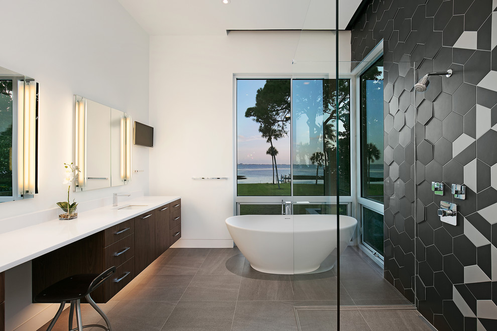 Inspiration for a large modern master bathroom in Tampa with flat-panel cabinets, brown cabinets, a freestanding tub, a curbless shower, black and white tile, ceramic tile, white walls, porcelain floors, an undermount sink, engineered quartz benchtops, grey floor, a hinged shower door, white benchtops and a wall-mount toilet.