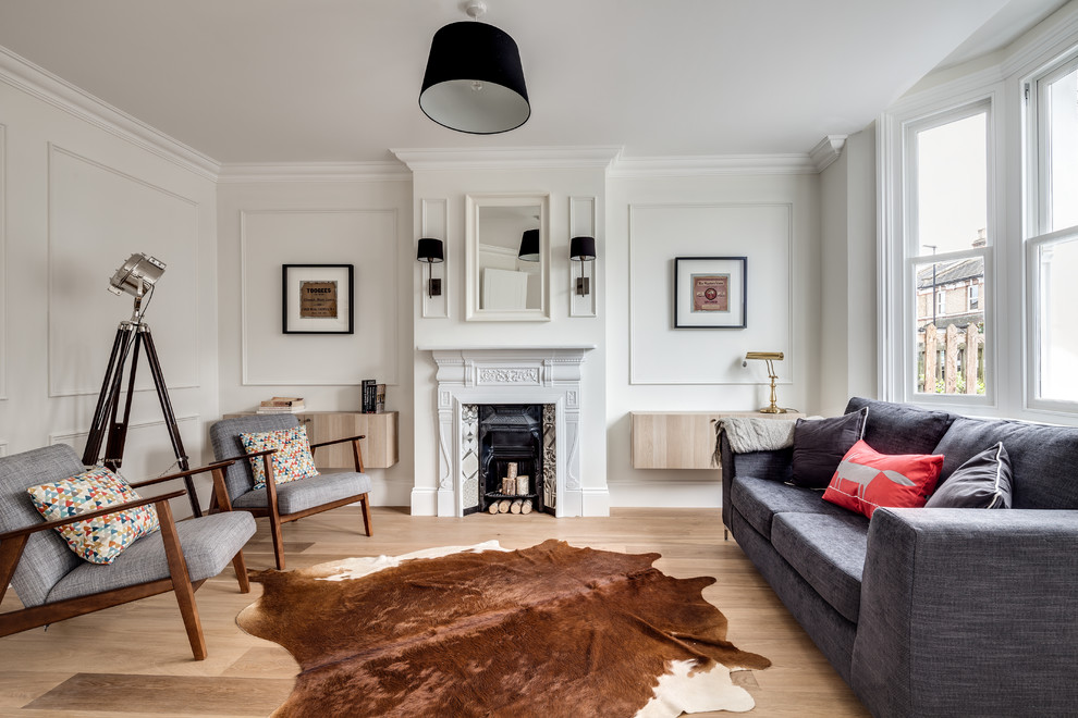 This is an example of a scandinavian formal living room in London with white walls, light hardwood floors and a standard fireplace.