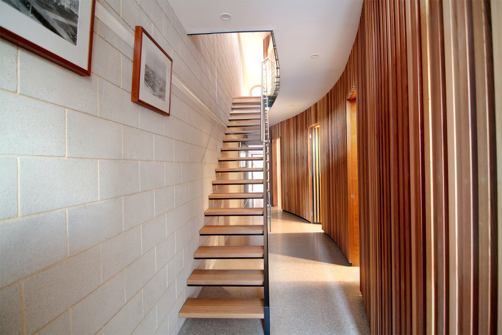 This is an example of a mid-sized contemporary wood straight staircase in Other with open risers and glass railing.