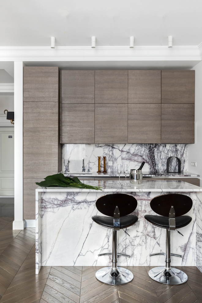 Contemporary galley kitchen in Moscow with flat-panel cabinets, medium wood cabinets, marble benchtops, white splashback, marble splashback, medium hardwood floors, with island, brown floor and white benchtop.