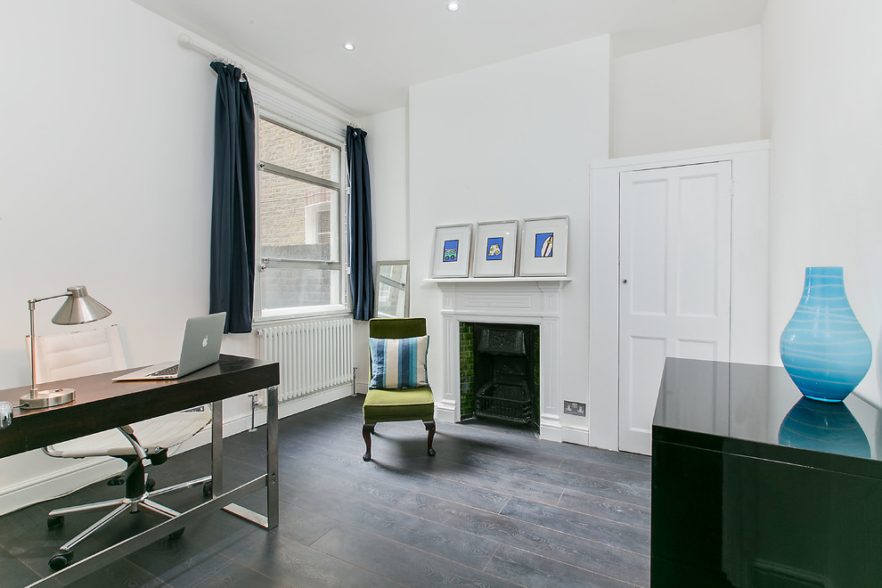 Photo of a mid-sized transitional study room in London with white walls, dark hardwood floors, a standard fireplace, a freestanding desk and a tile fireplace surround.