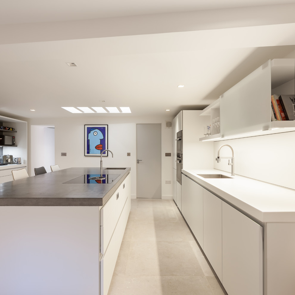 Inspiration for a mid-sized contemporary kitchen in London with flat-panel cabinets, white cabinets, white splashback, stainless steel appliances, cement tiles, with island, a single-bowl sink, beige floor and white benchtop.