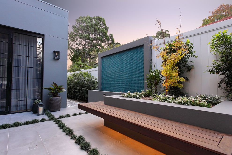 This is an example of a large contemporary courtyard shaded formal garden for winter in Sydney with a water feature and natural stone pavers.