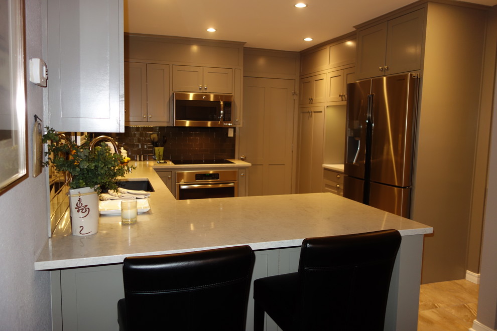 Inspiration for a small transitional u-shaped ceramic tile home design remodel with an undermount sink, shaker cabinets, gray cabinets, quartz countertops, gray backsplash, glass tile backsplash, stainless steel appliances and a peninsula