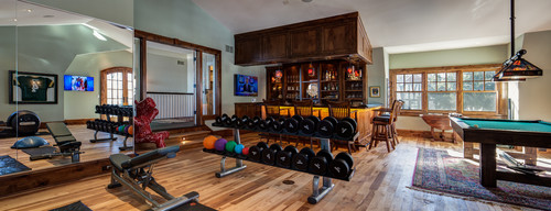 Home gym setup next to in-home bar and billiard table