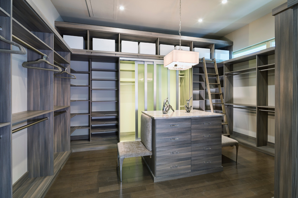 This is an example of a mid-sized modern gender-neutral walk-in wardrobe in Los Angeles with flat-panel cabinets, dark wood cabinets and medium hardwood floors.