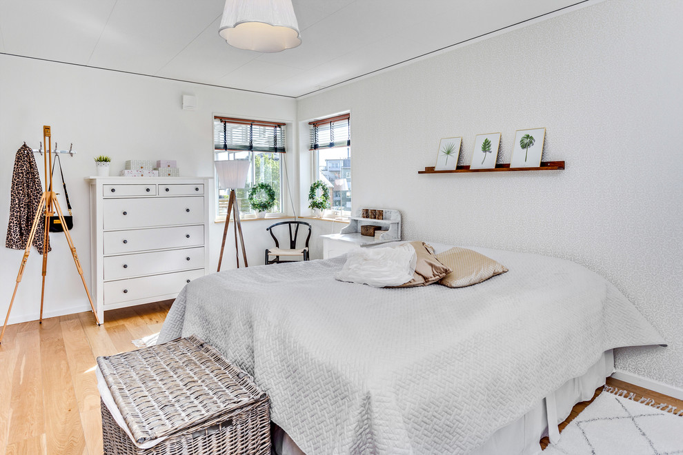 Large scandinavian master bedroom in Stockholm with white walls and light hardwood floors.