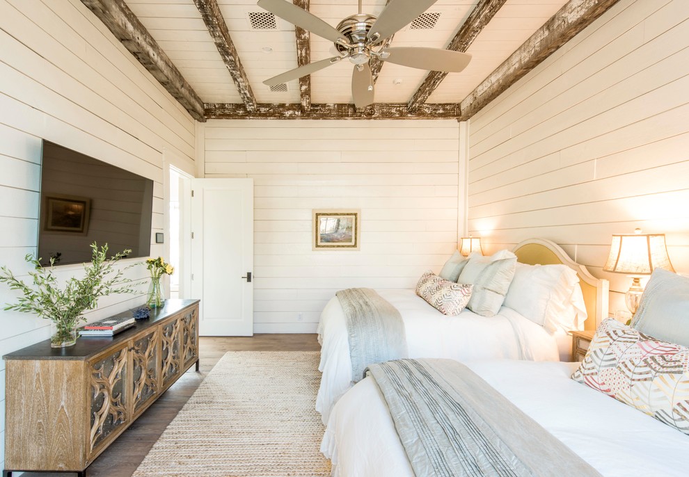This is an example of a country guest bedroom in Austin with white walls, dark hardwood floors and no fireplace.