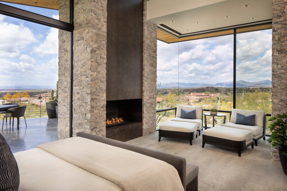 Inspiration for an expansive modern master bedroom in Phoenix with white walls, limestone flooring, a two-sided fireplace, a stone fireplace surround and grey floors.