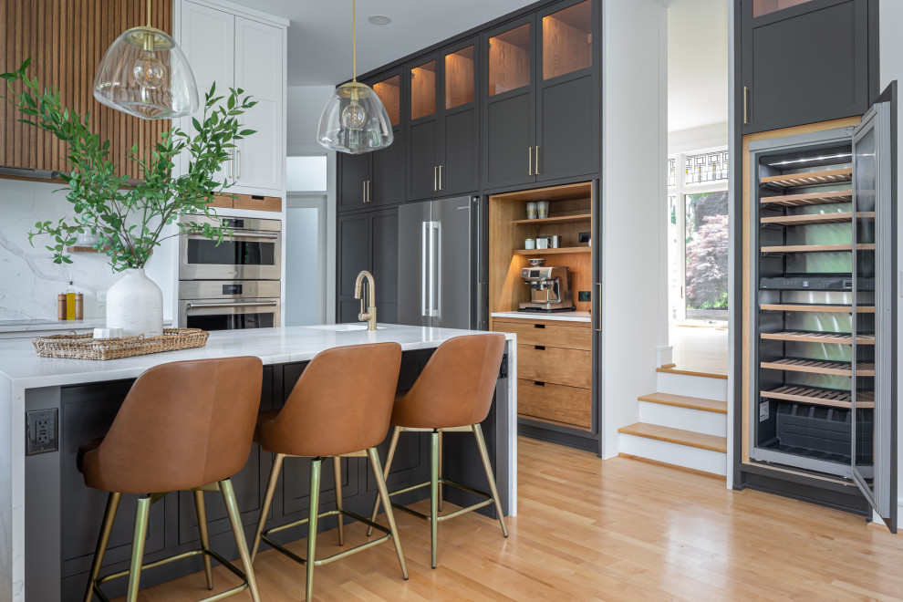 Large transitional u-shaped medium tone wood floor and brown floor enclosed kitchen photo in Raleigh with an undermount sink, shaker cabinets, white cabinets, quartz countertops, white backsplash, quartz backsplash, stainless steel appliances, an island and white countertops